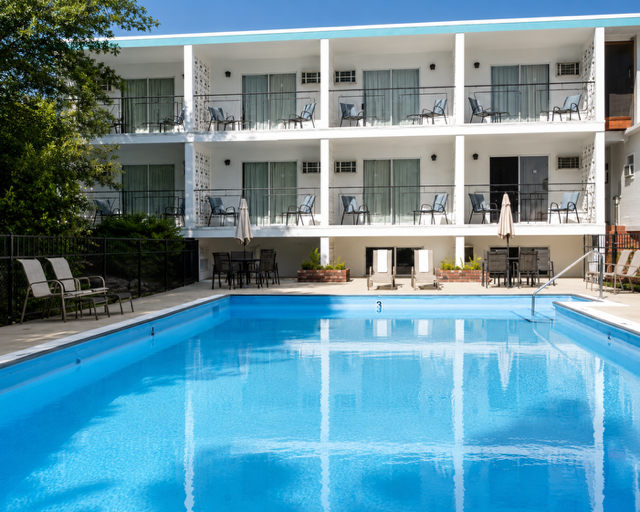 Schell Motel exterior: white facade, teal trim, blue pool, two-storey U-shape with balconies